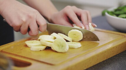 Close up of Woman cut a peeled banana to make the smoothie