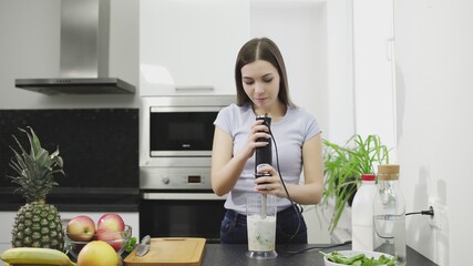 Beautiful young woman is making the smoothie of cocktail with milk in blender