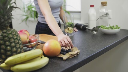 Woman takes blueberries making the smoothie with milk in blender