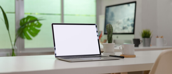 Blank screen laptop on white desk with office supplies in modern office room