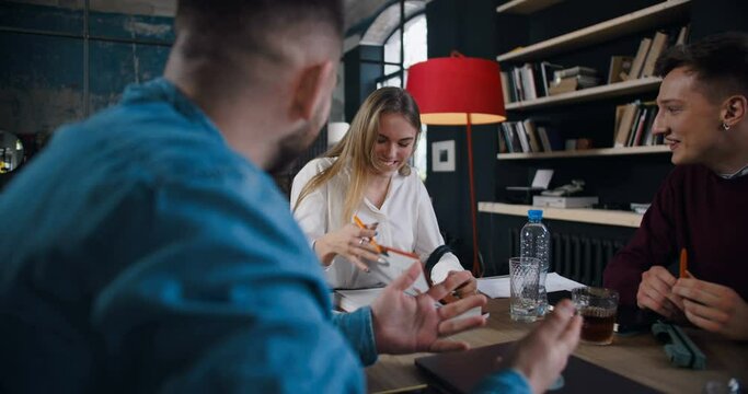 Beautiful excited young blonde female boss laughs working with diverse start-up team at modern light trendy coworking.