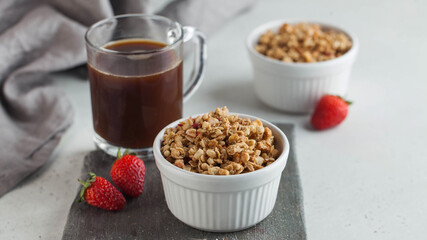 Homemade granola in a white bowl with strawberries and a Cup of coffee. The concept of a healthy Breakfast.