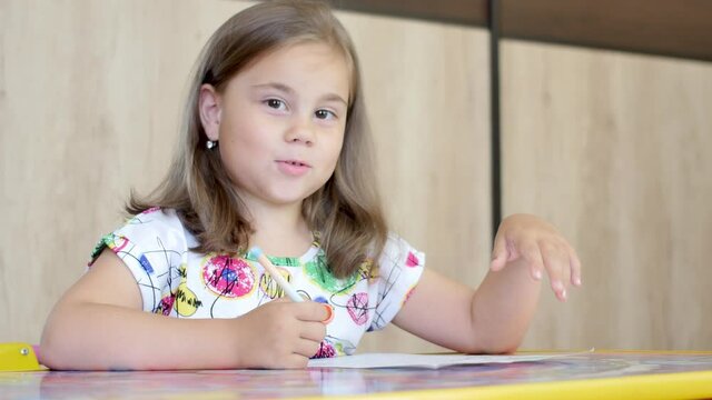 Happy little girl or cute primary child school child painting or writening on paper. Children elementary education concept.
