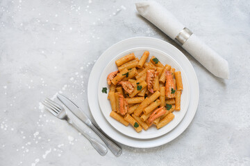 Penne pasta or Italian rigatoni with langoustines and  tomato sauce in white plate top view. seafood pasta recipe