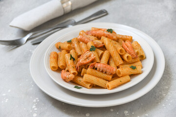 Penne pasta or Italian rigatoni with langoustines and  tomato sauce in white plate top view. seafood pasta recipe