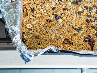 Home made energy granola with nuts, dried fruit, peanut butter and superfoods baked in baking tin.