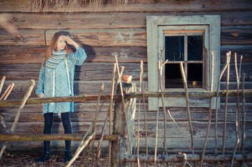 Fototapeta premium Portrait of a young attractive girl in a vintage style wearing knitted hat and shawl walking in the countryside