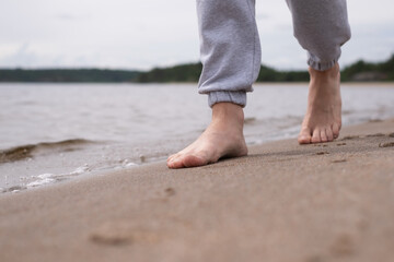 Male feet barefoot on a sandy beach in the water. Close-up of male legs.