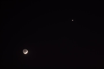 Young Moon and Venus on a dark night sky.