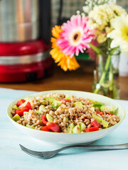 Fresh Italian farro spelt salad with tomatoes, avocado and cucumbers on wooden turquoise board. Easy recipe whole food meal