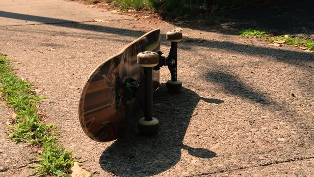 A skateboard sits on its side in the hot sun of summer.