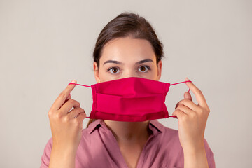 Young girl looking at the camera and preparing to put on a mask. Woman on a light background...