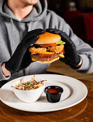 man in black gloves eating burger in the restaurant