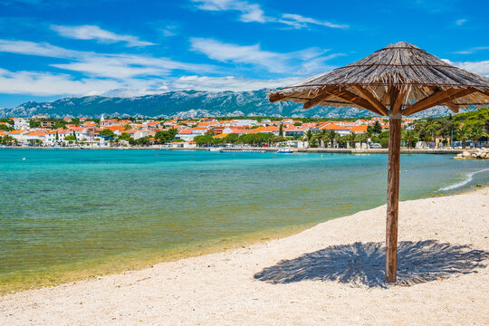 Adriatic sea shore in Croatia on Pag island, parasol on beautiful sand beach in town of Novalja
