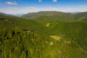 European countryside forests from aerial view in summer nature at sunset. Scenic capture of a small slade surrounded by forested hills in good weather.