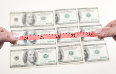 Male hands with measuring tape and dollars.