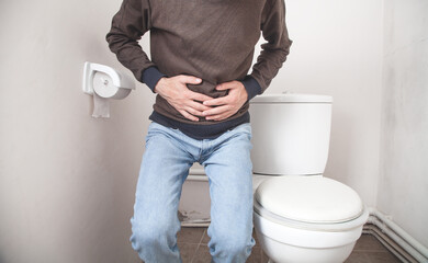 Caucasian man in toilet. Concept of abdominal pain, diarrhea
