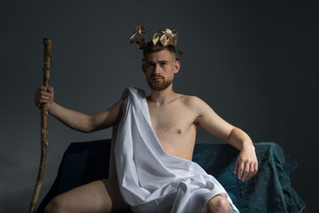 Portrait of the ancient Greek god Olympus, in white clothes, with a wreath on his head, holds a...
