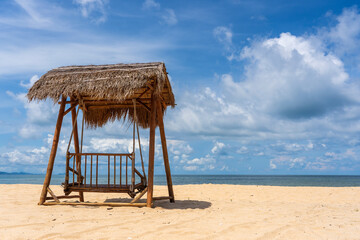 Wooden swing under a thatched roof on a sandy tropical beach near sea on island of Phu Quoc, Vietnam. Travel and nature concept
