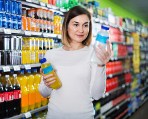 Young woman choosing refreshing beverages in supermarket