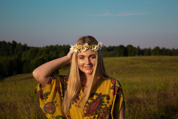 Russian slavic girl in field in the summer, with a wreath on her head