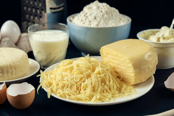 Blue bowl with floor, few types of cheese, milk, eggs, grater – preparation for making pie, pizza, baking. Process of cooking Adjaruli Khachapuri. Adjarian Khachapuri Recipe – Georgian cheese bread.