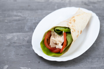 chicken and salad tortilla wraps on white dish on ceramic background