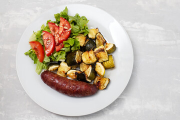 sausage with grilled vegetables and fresh salad on plate