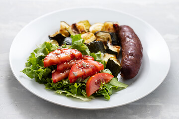 sausage with grilled vegetables and fresh salad on plate