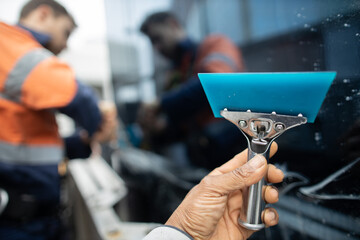 Holding industry blue rubber sealing window with defocused worker sealing cleaning window at the background 