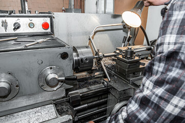 master grinds metal product. The old Metalworking machine, manufactured in the middle of the last century, is still in good condition.