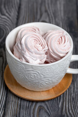 Homemade zephyr in a mug. On the surface of pine boards painted in black and white.