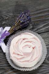 Homemade zephyr in the shape of a rose. Near a bunch of lavender. On the surface of pine boards painted in black and white. Shot from above.