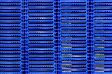 Fototapeta na wymiar Columns of stacked blue plastic berry trays form a pleasant geometric pattern.