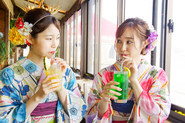 海沿いのカフェで休憩する二人の浴衣の女性