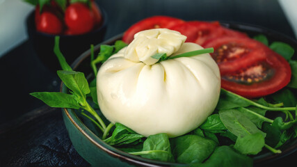 burrata. dinner with tomato and spinach salad with Italian Buratto cheese. Concept of healthy Mediterranean food