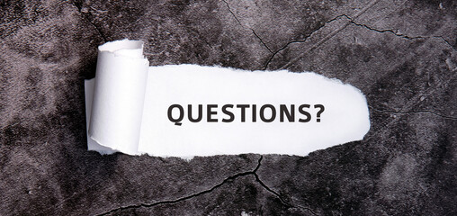 Questions with torn white paper on a gray concrete table