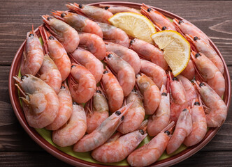 Freshly cooked prawns in a plate on a wooden table. Close up.
