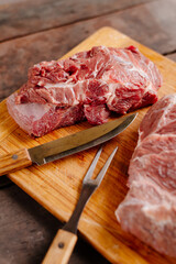 Raw beef. A piece of raw beef cut in half. Raw beef in front of the grill. Grill in the background.