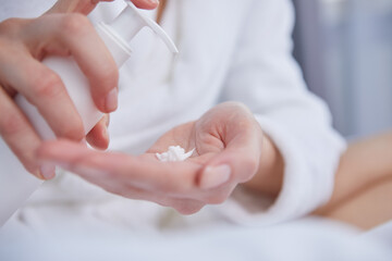 Young woman applying hand cream at home, closeup