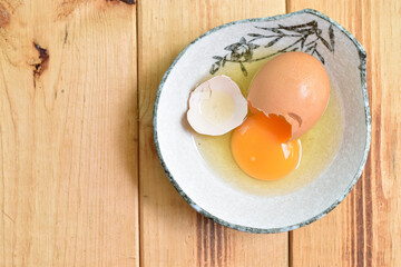 Cracked egg yolks and eggs in a ceramic bowl