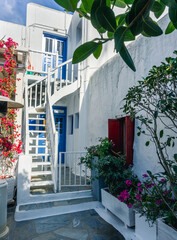 Colorful houses, blue and red doors and windows and lots of flowers in the old town of Mykonos Island, Greece.
