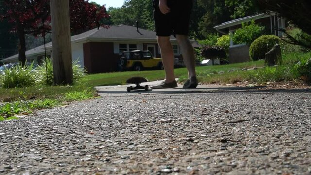 Setting down a skateboard on a suburban neighborhood sidewalk.