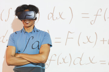 Portrait of smiling mixed race student boy in virtual reality headset standing with crossed arms against projection screen with math formula