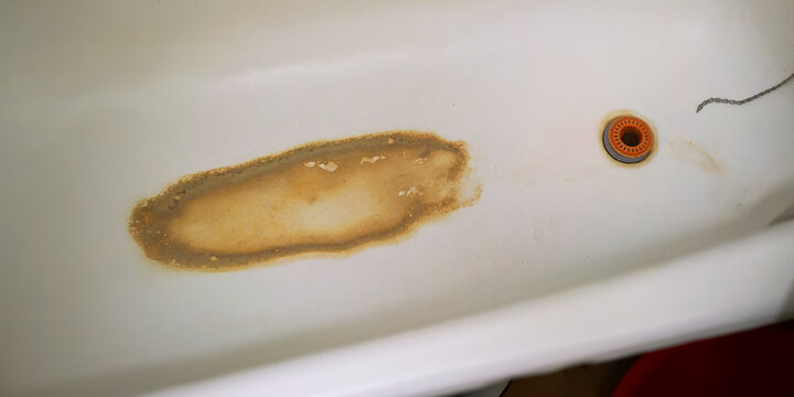 outdated white bath with brown dirt and rust on bottom