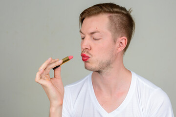 Portrait of young man with beard stubble wearing makeup