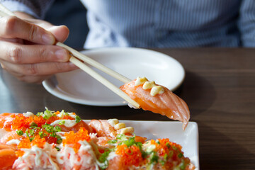 People use chopsticks to pick up sushi.