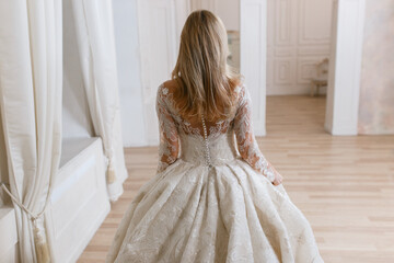 Fototapeta premium Bride in a magnificent wedding dress posing in a light interior photo studio. Vintage design