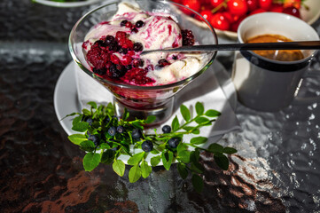 Vanille ice cream with berries, twig with blueberries, reed cherry on plate.