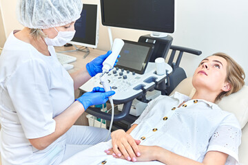 girl at the doctor’s office. ultrasound study. doctor puts gel on equipment